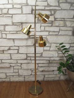 a floor lamp that is on top of a wooden floor next to a brick wall