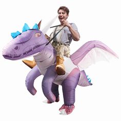 a man riding on the back of a purple dragon inflatable costume with wings