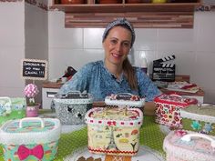 a woman sitting at a table in front of many cakes and baskets on display for sale