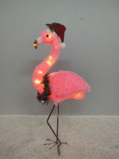 a pink flamingo wearing a santa hat with lights on it's head and legs