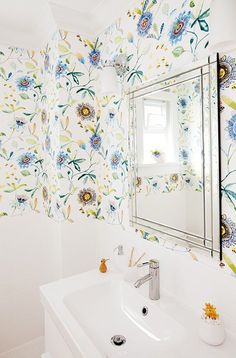 a white sink sitting under a bathroom mirror next to a wall mounted faucet