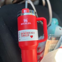 a red travel mug sitting on top of a car seat