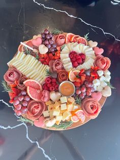 a platter filled with fruit and cheese on top of a table