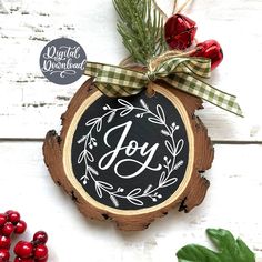 a wooden ornament with the word joy painted on it next to berries and greenery