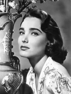 a black and white photo of a woman next to a vase