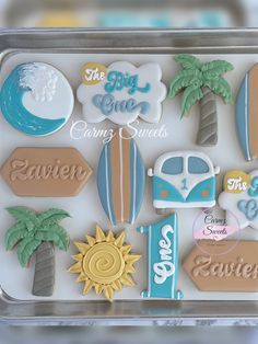 some cookies are in a plastic container on a table and one is decorated with palm trees, the other has surfboards