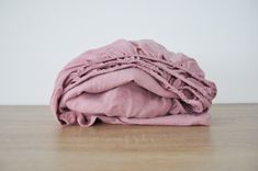 an unmade pink blanket sitting on top of a wooden table next to a white wall