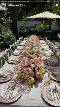 a long table with plates and flowers on it is set for an outdoor dinner party