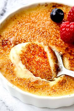 a close up of a bowl of food with fruit on the side and a spoon in it