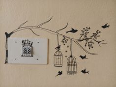 a birdcage with two birds hanging from it next to a wall mounted light switch