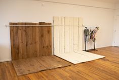 an empty room with wood flooring and clothes on hangers in the corner,