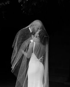 a woman in a wedding dress and veil kissing a man on the forehead with his arm around her