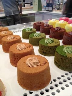 there are many different cakes on the trays in this display case, including one with chocolate and green frosting