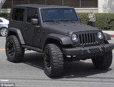 a black jeep is parked in front of a parking meter and another car behind it