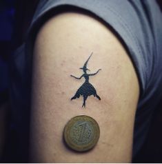 a woman's arm with a tattoo on it and a coin in front of her