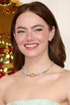 a woman in a strapless dress smiles at the camera while wearing a diamond necklace