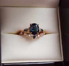 an engagement ring with blue and white stones in a box on top of a table