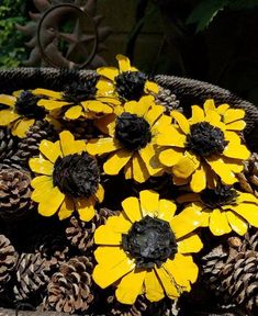 some yellow flowers are sitting in a basket full of pinecones and blackberries