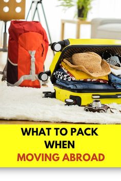 an open yellow suitcase with clothes and hats in it sitting on a white area rug