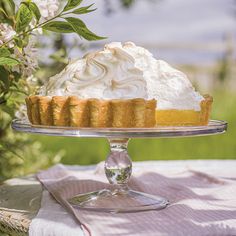 a pie on a glass cake plate with flowers in the background