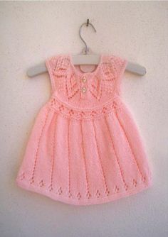 a pink knitted dress hanging on a white wall with a hanger attached to it