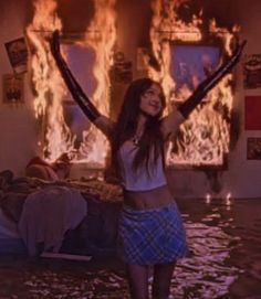 a woman standing in the middle of a flooded room with her arms up and hands raised above her head