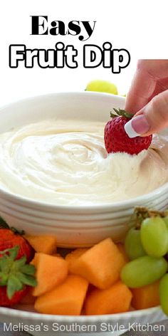 a person dipping fruit into a bowl with dip in the middle and other fruits around it