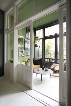 an open door leading to a living room with green walls and white flooring on the side