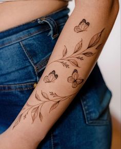 a woman's arm with flowers and butterflies tattooed on the side of her arm