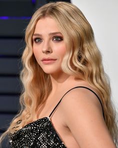 a woman with long blonde hair wearing a black dress