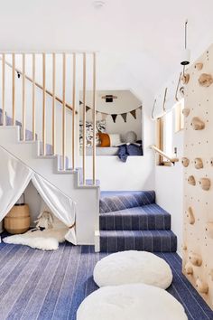 there is a climbing wall in the room with blue carpet and white rugs on the floor