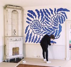 a man is painting on the wall in his living room with blue and white paint