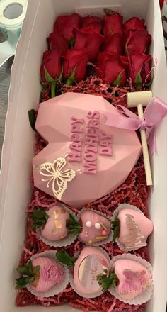 a box filled with lots of pink chocolates next to red roses on a table