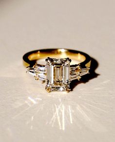 an engagement ring with three baguets on the side and one stone in the middle