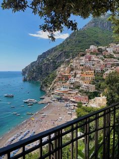 the beach is lined with boats and houses on the hill side, overlooking the ocean