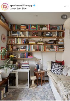 a living room filled with lots of books on shelves next to a couch and table