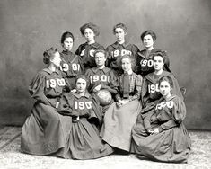 an old black and white photo of women in long dresses with numbers on their shirts