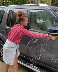 a woman is washing her car with a sponge