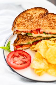 a grilled cheese sandwich with chips and tomatoes