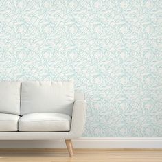 a white couch sitting in front of a pink wallpapered room with a wooden floor