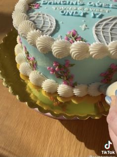 someone is decorating a birthday cake with frosting and flowers on the bottom layer