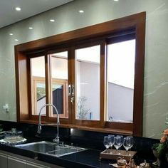 a kitchen counter with two wine glasses on it, and an open window above the sink