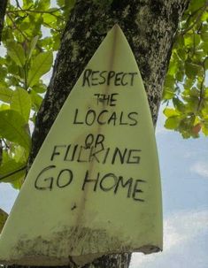 a surfboard that has been placed on the side of a tree with graffiti written on it