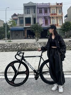 a person standing next to a bike on the street with buildings in the background,