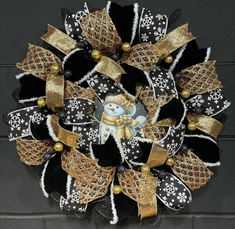 a black and gold christmas wreath with snowman on it's front door ornament