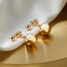 Gleaming 10mm white shell pearls on golden beads add just the right touch to your ensemble! The hanging length is 20mm (3/4"). The metal part is gold-plated and friendly to the skin. * Buy over 2 pieces and get a medium jewelry organizer* Buy over $100 and get a large mirror jewelry organizer Minimalism gold pearl earrings Take a look at our beautiful pearl earring design. These pearl drop earrings have been designed by a nature-originated jewelry designer and are made with faux pearls to give y