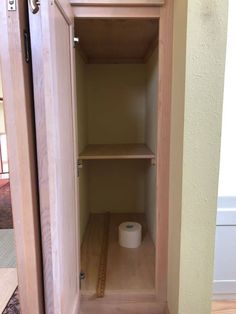 an empty closet with a toilet paper roll on the floor and a tape measure in front of it