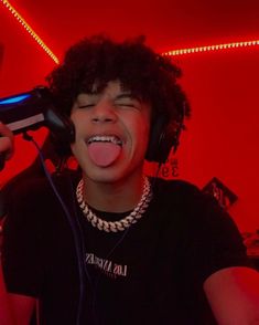 a young man with headphones on singing into a microphone and holding his tongue out