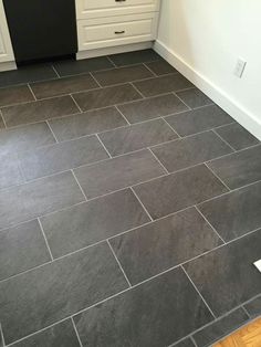 a kitchen with black tile flooring and white cabinets on the walls, along with a dishwasher