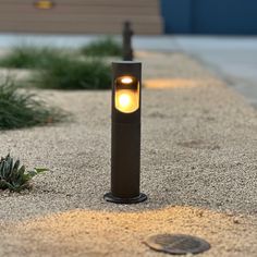 a street light sitting on the side of a road next to a planter filled with flowers